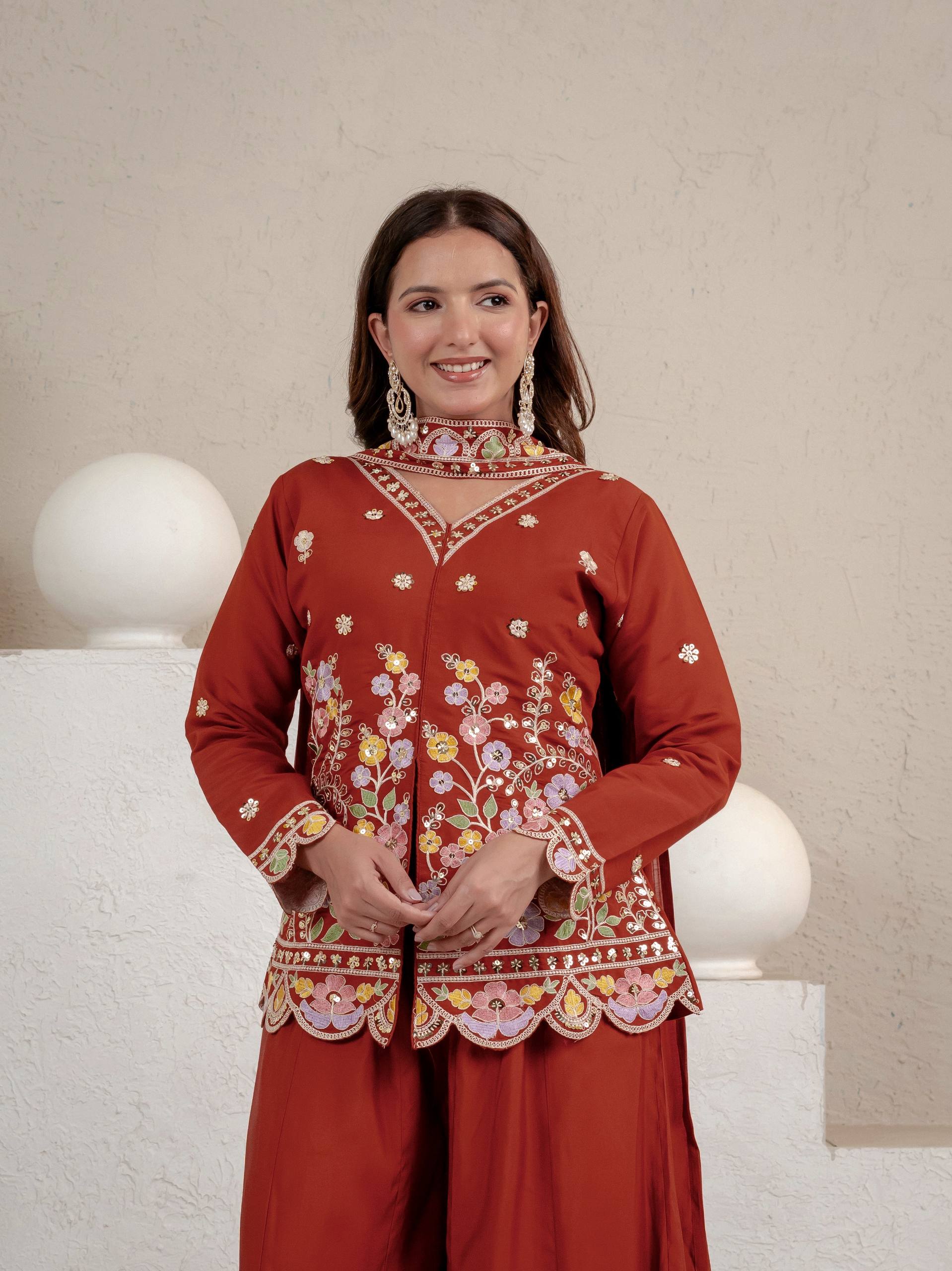 Resplendent Rust Orange Peplum Kurti and Flared Palazzo Suit Set Adorned with Intricate Multicolored Floral Embroidery, Sequin Accents, and Ornate Scalloped Borders